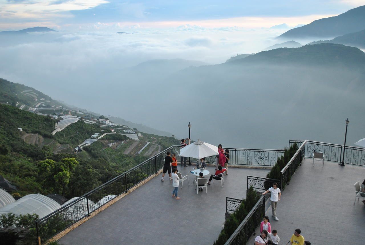 Una terraza con gente, una mesa y sillas, con vistas a un paisaje montañoso.