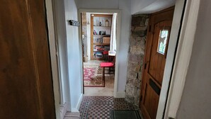 A hallway with a checkered floor, a wooden door, and a view into a room with a bookshelf and a red chair. - Character cottage (18c) on the edge of historic Belper (Belper)