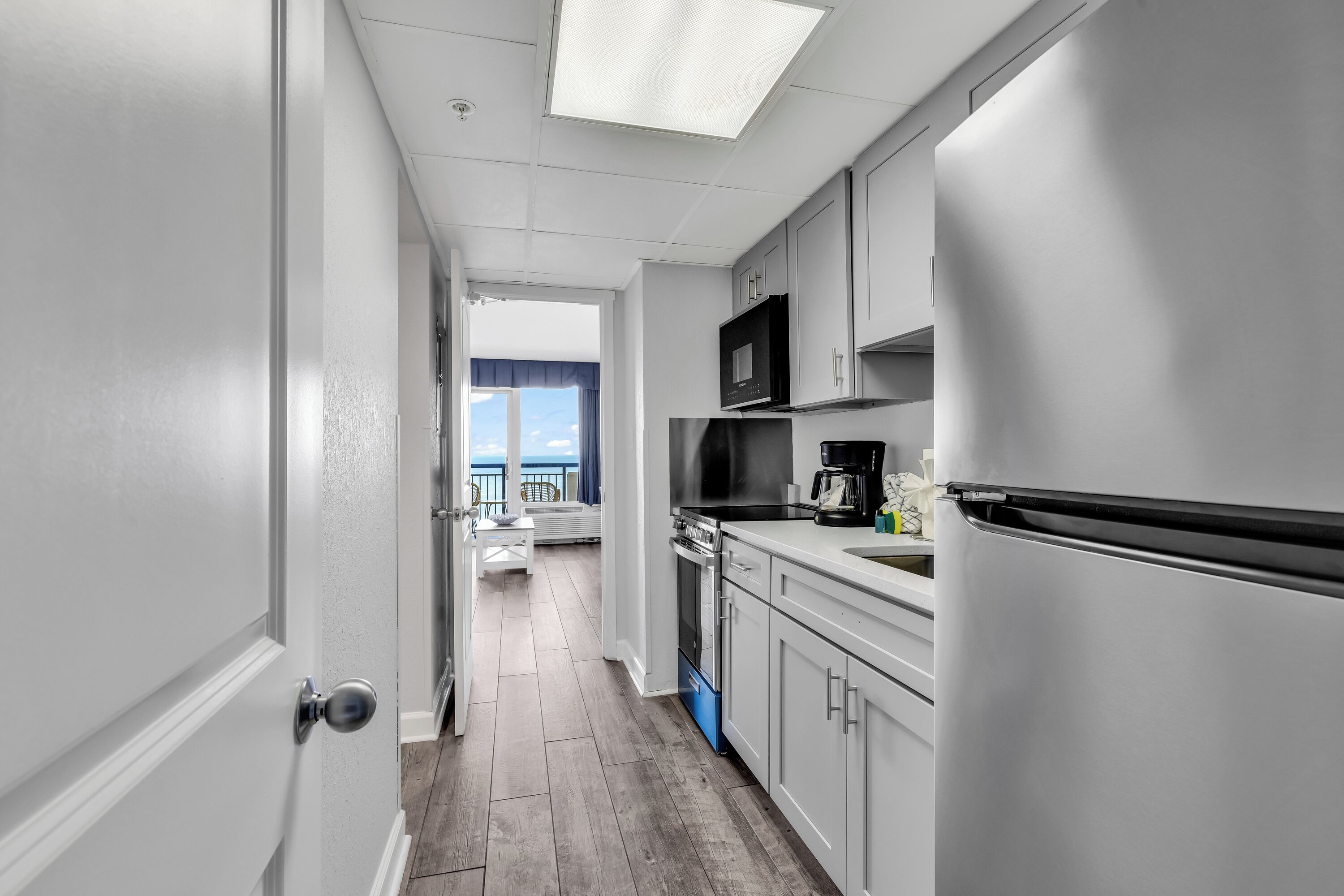 A modern kitchen with white cabinetry, a microwave, a stove, and a refrigerator.