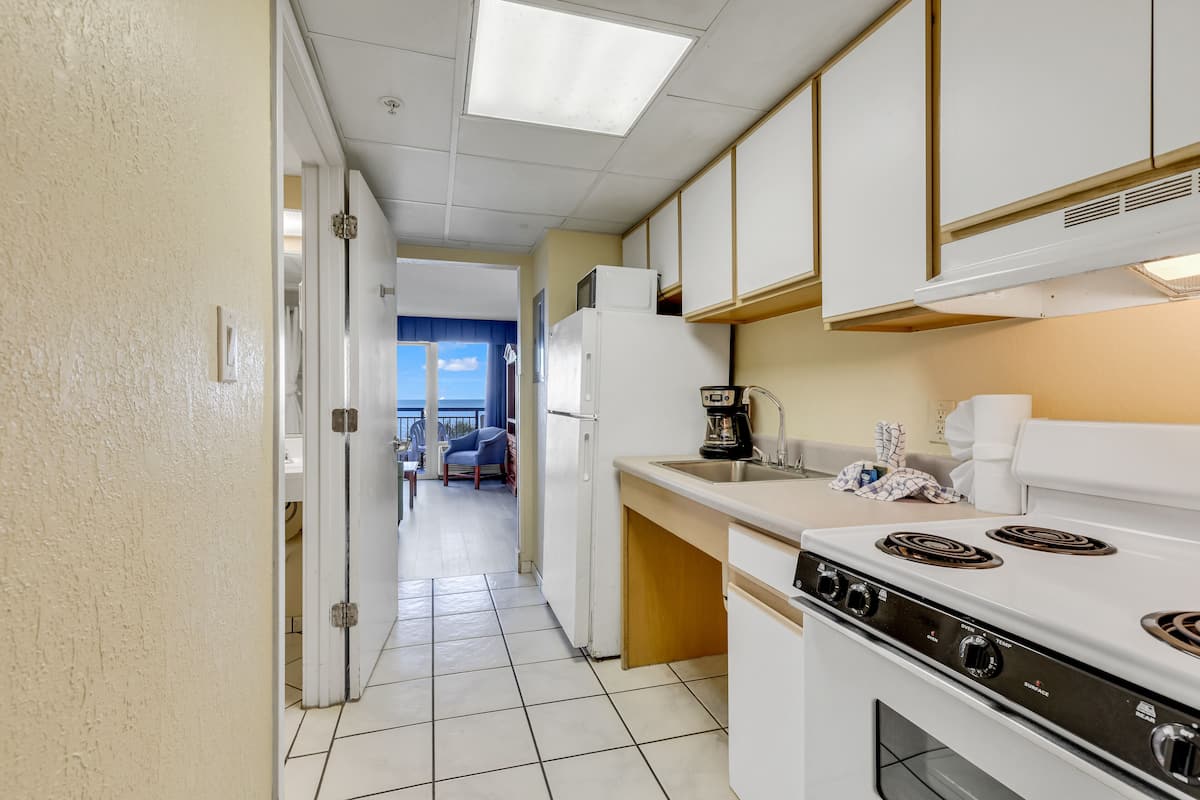 A kitchen with white cabinets, a stove, and a coffee maker.