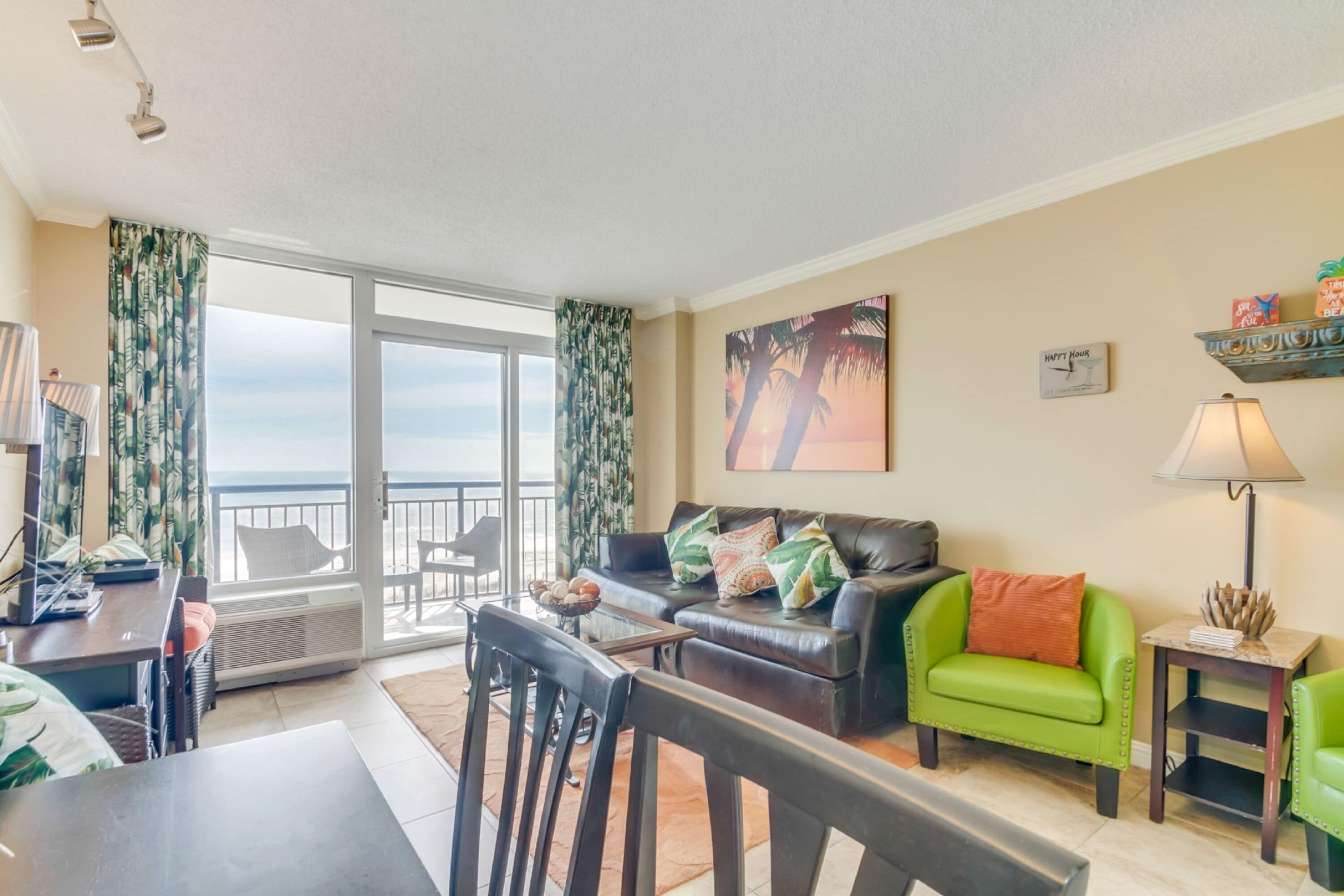 A living room with a sofa, chairs, a coffee table, and a view of the ocean through large windows.