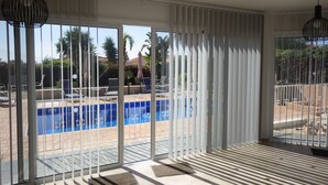 A spacious room with large sliding glass doors leading to a pool area, featuring a clear view of the pool and surrounding greenery. - Villa, sea views, FREE A/C, pool, roof terrace, Wifi (Peyia)
