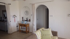 A living room with a sofa, a small table, and a door leading to another room. - Villa, sea views, FREE A/C, pool, roof terrace, Wifi (Peyia)
