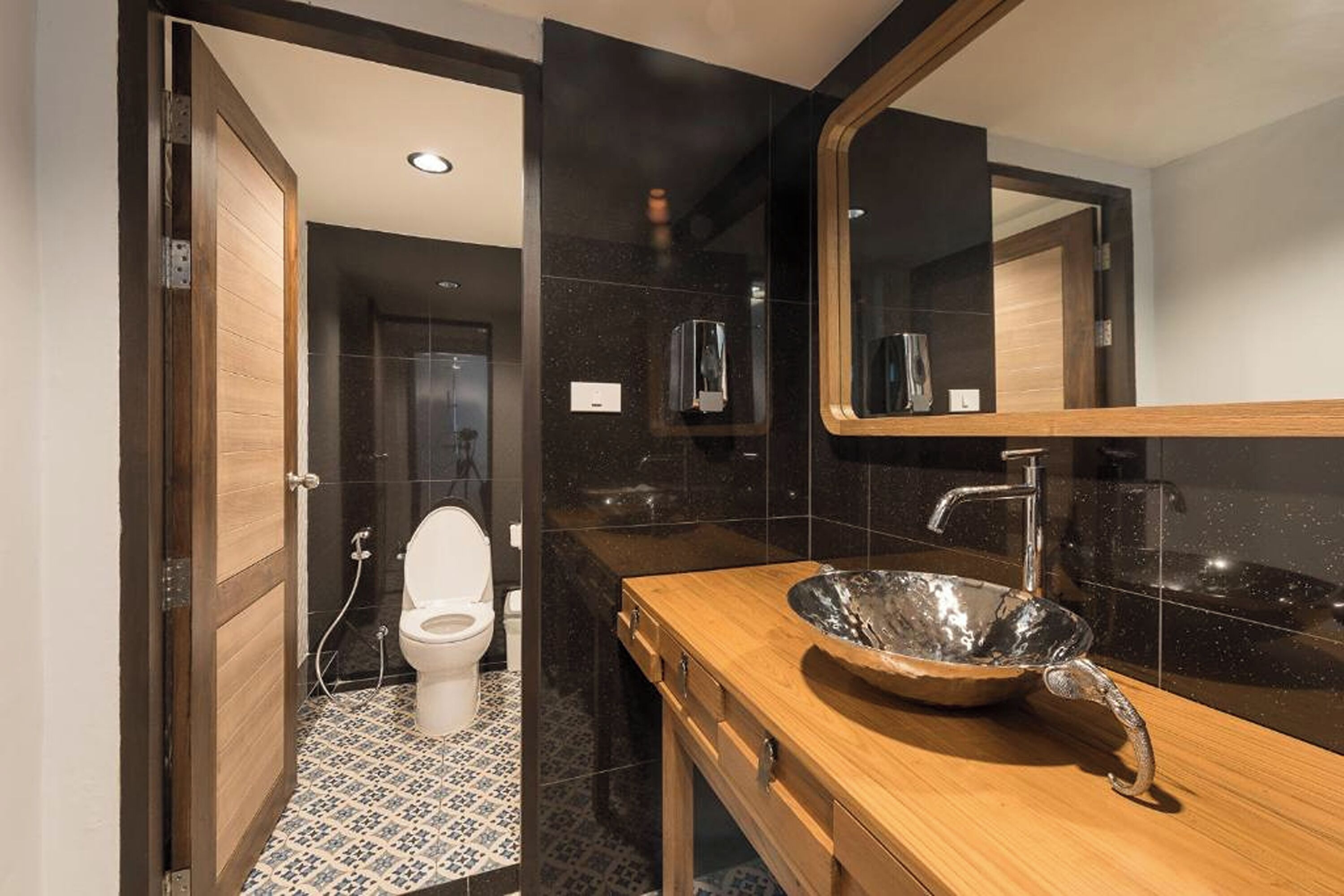 A modern bathroom with a wooden vanity, a large mirror, and a unique bowl sink.