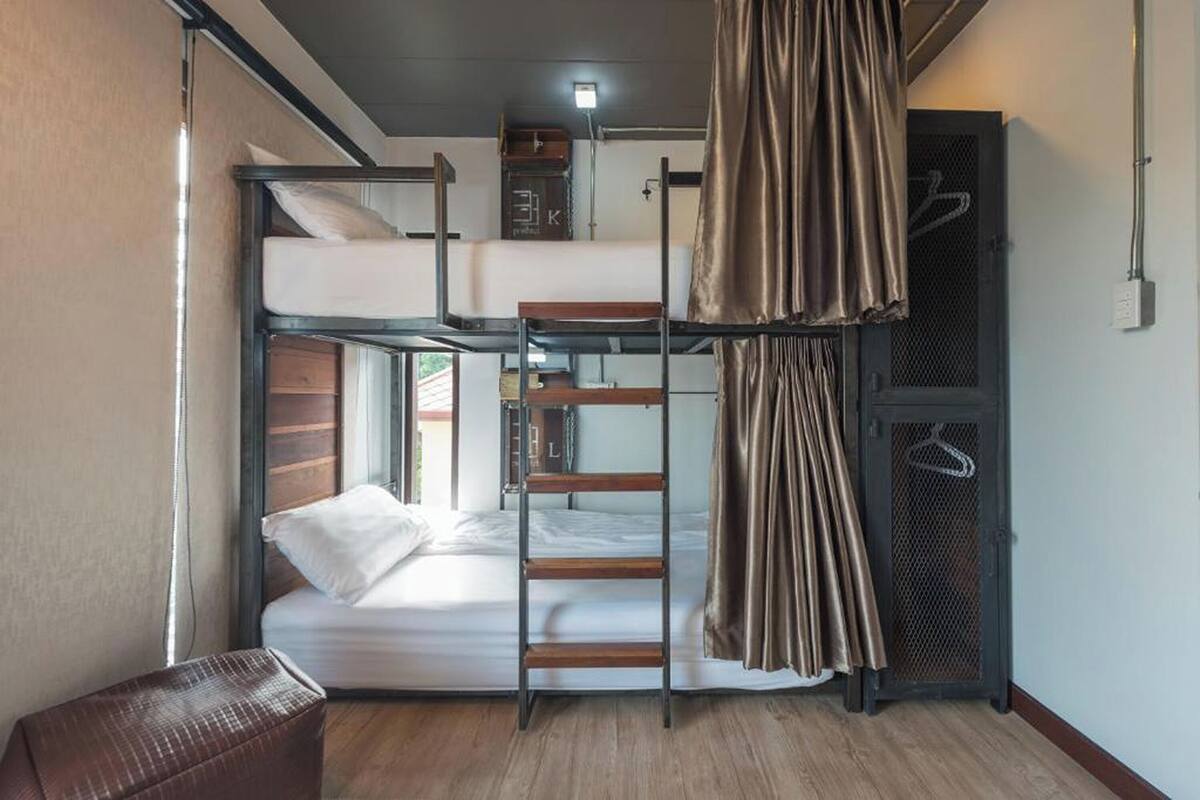 A bunk bed room with a ladder, a small table, and a curtain.