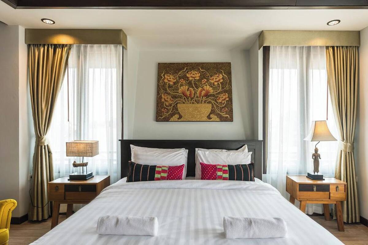 A hotel room with a large bed, two bedside tables, a lamp on each table, and a painting above the bed.