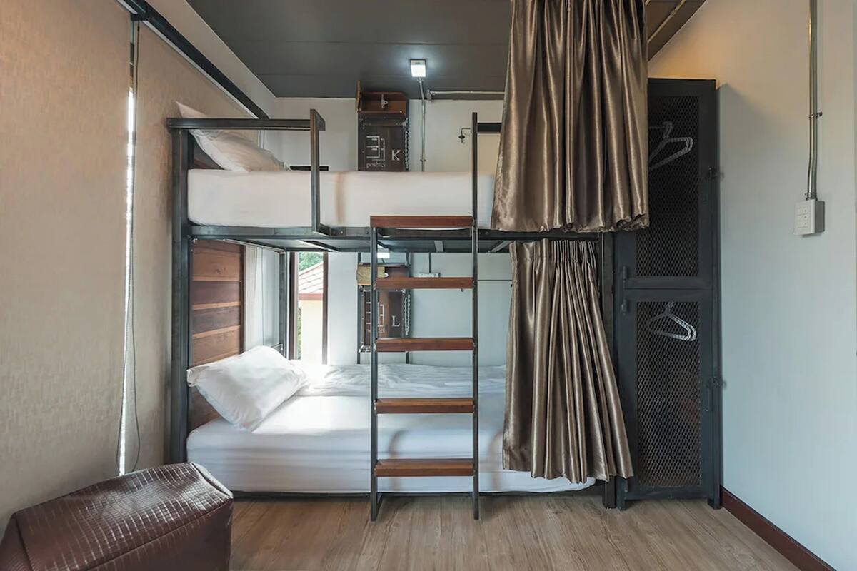 A bunk bed room with a ladder, a small table, and a hanging curtain.