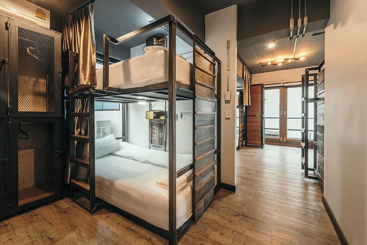 A compact room with a bunk bed, a small desk, a chair, and a wardrobe.