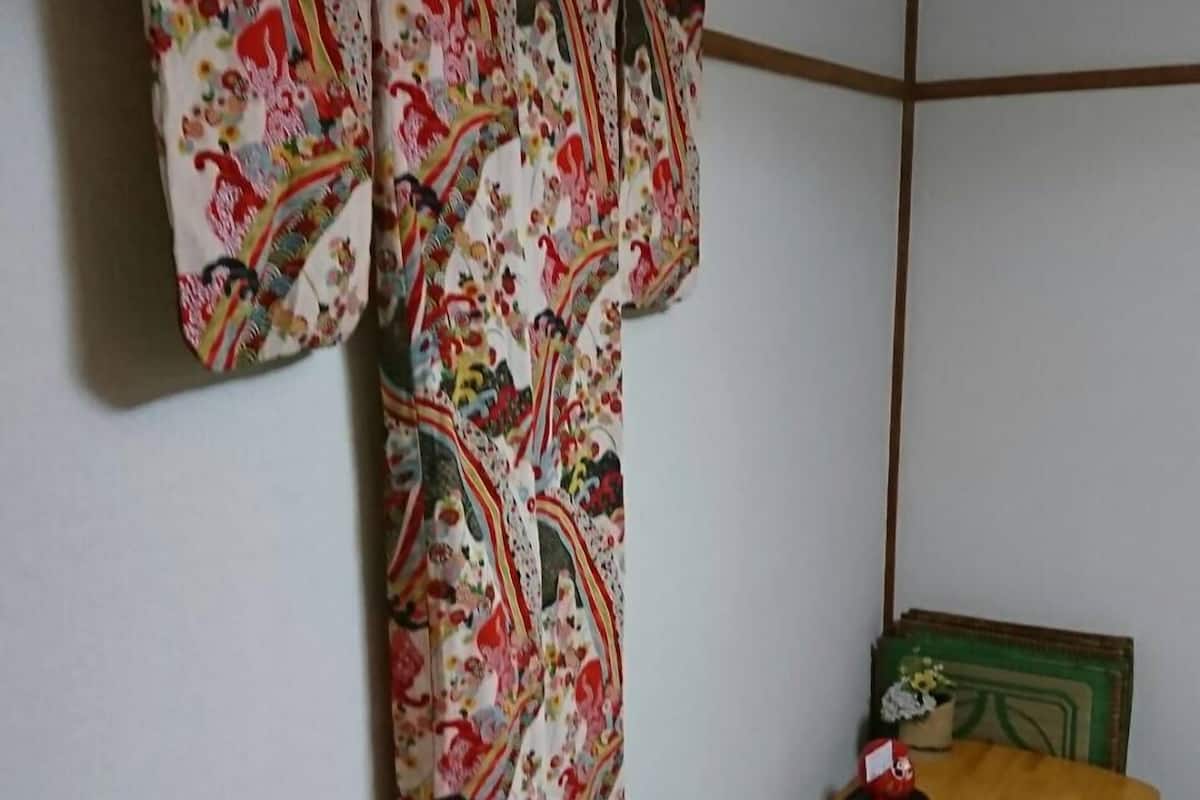 A traditional Japanese room with tatami flooring, a low wooden table, and a colorful hanging textile.