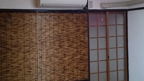 A traditional Japanese room with tatami flooring, a shoji screen, and a sliding door. - Abiko Guest House (Osaka)