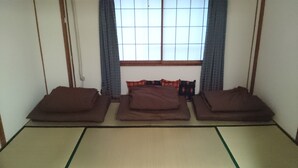 A tatami mat room with three tatami mats and a futon bed with pillows. - Abiko Guest House (Osaka)