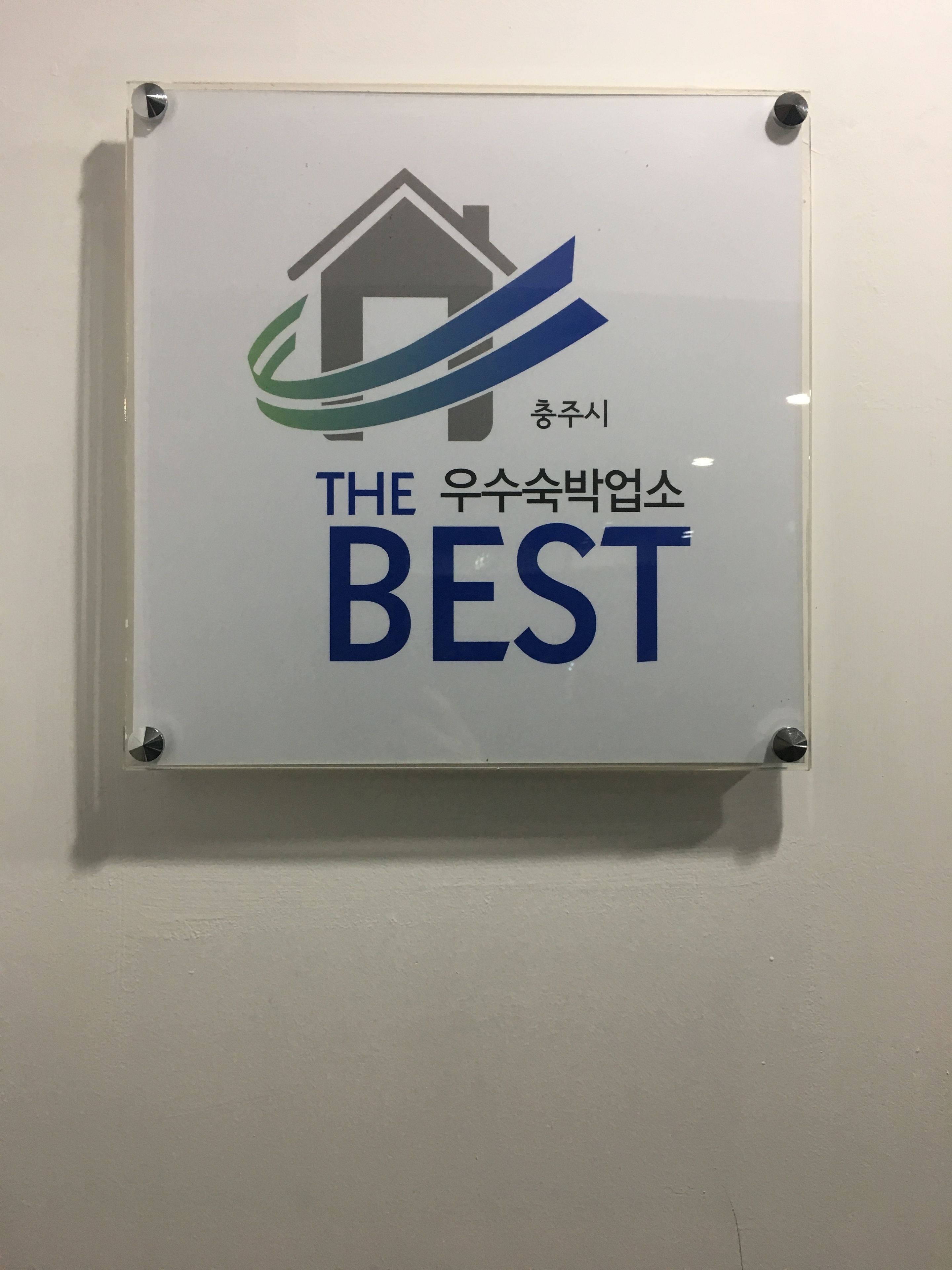 Un letrero con una imagen de una casa y un diseño ondulado, y texto en inglés y coreano.