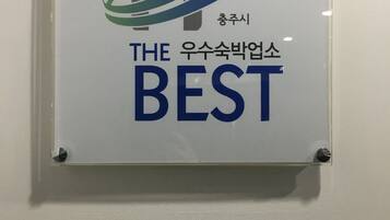 Un letrero con una imagen de una casa y un diseño ondulado, y texto en inglés y coreano.