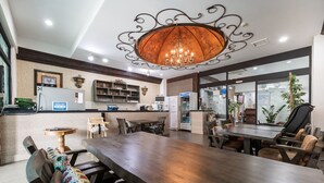 A spacious dining area with a large wooden table and multiple chairs, a kitchen area with modern appliances, and a decorative chandelier. - Suanbo Hotel Screen (Chungju)