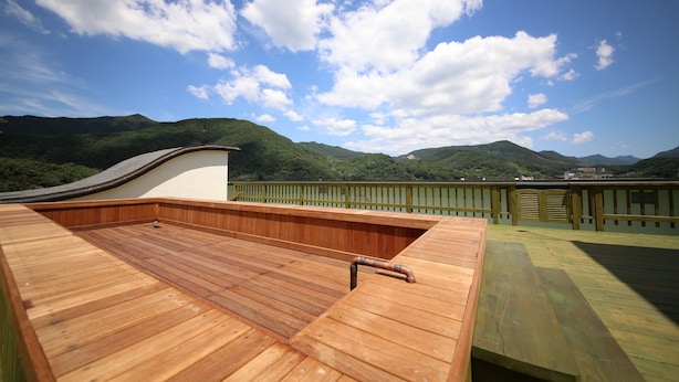 A wooden deck with a bench and a railing, overlooking a mountainous landscape. - Suanbo Hotel Screen (Chungju)