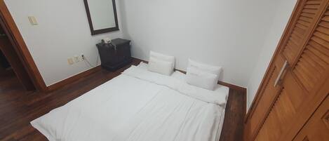 A bedroom with a bed, a nightstand, a mirror, and a wardrobe.