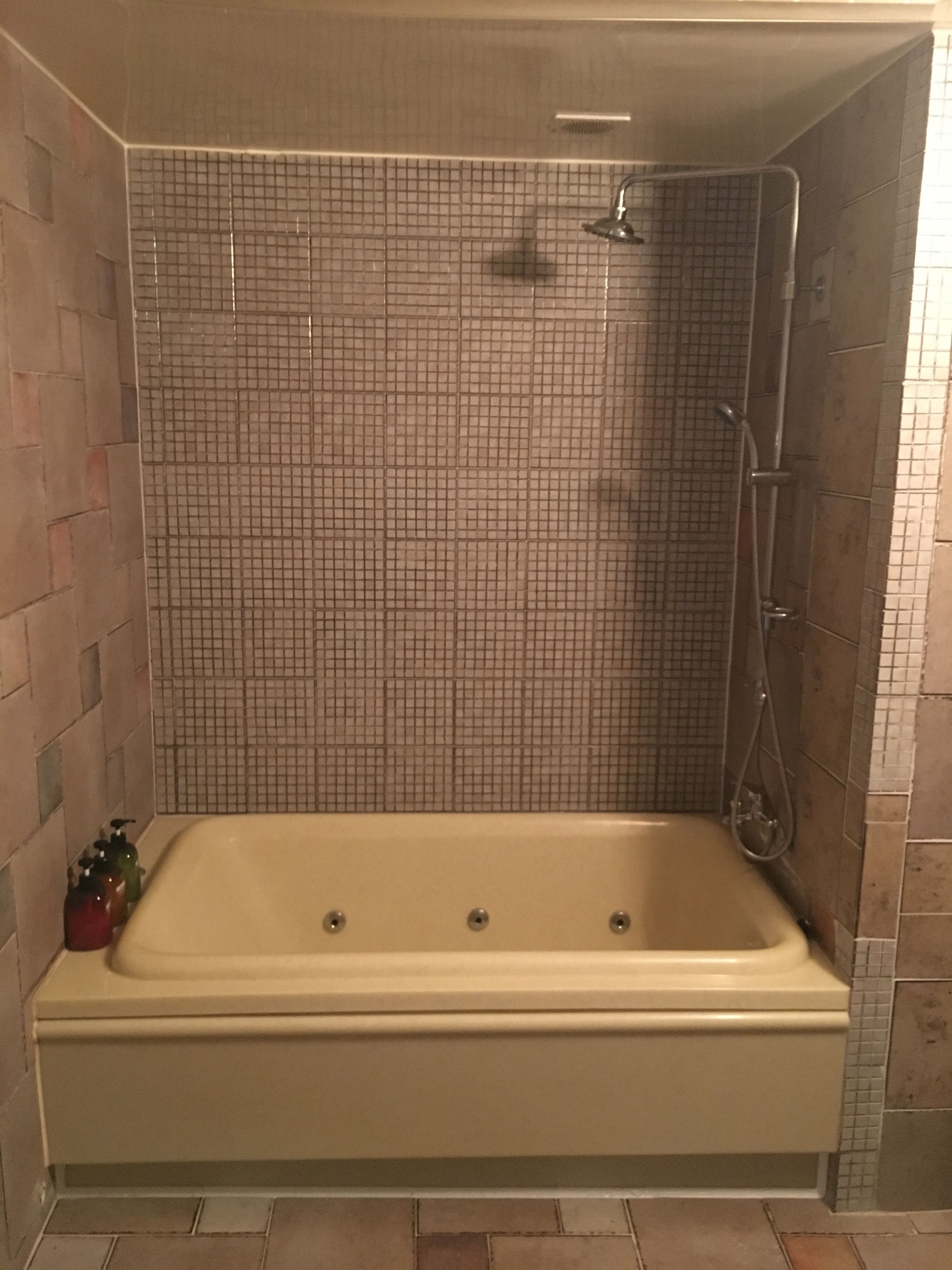 Un baño con una bañera grande, paredes de azulejos y zona de ducha.
