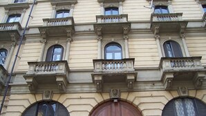 Un bâtiment doté d’une grande porte en bois, de nombreuses fenêtres avec volets et de balcons décoratifs.