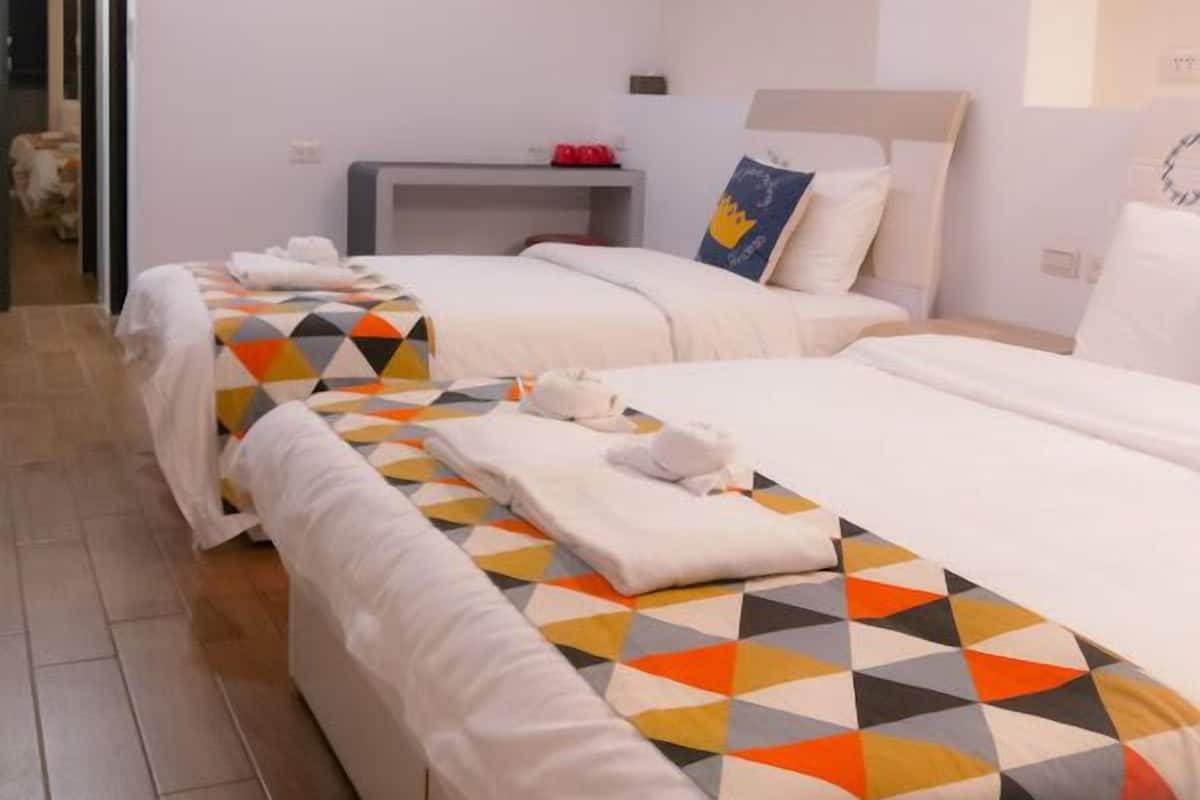 A hotel room with two beds, a bedside table, and a wall-mounted air conditioner.