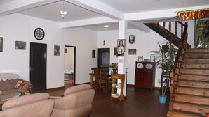 A spacious living room with a wooden staircase, a dining area, and a cozy seating area. - chez allen (Nuwara Eliya)
