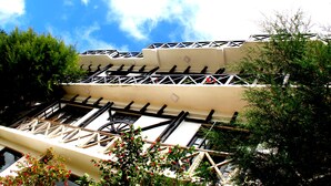 A building with a white facade, multiple balconies with black railings, and a clear blue sky in the background. - chez allen (Nuwara Eliya)