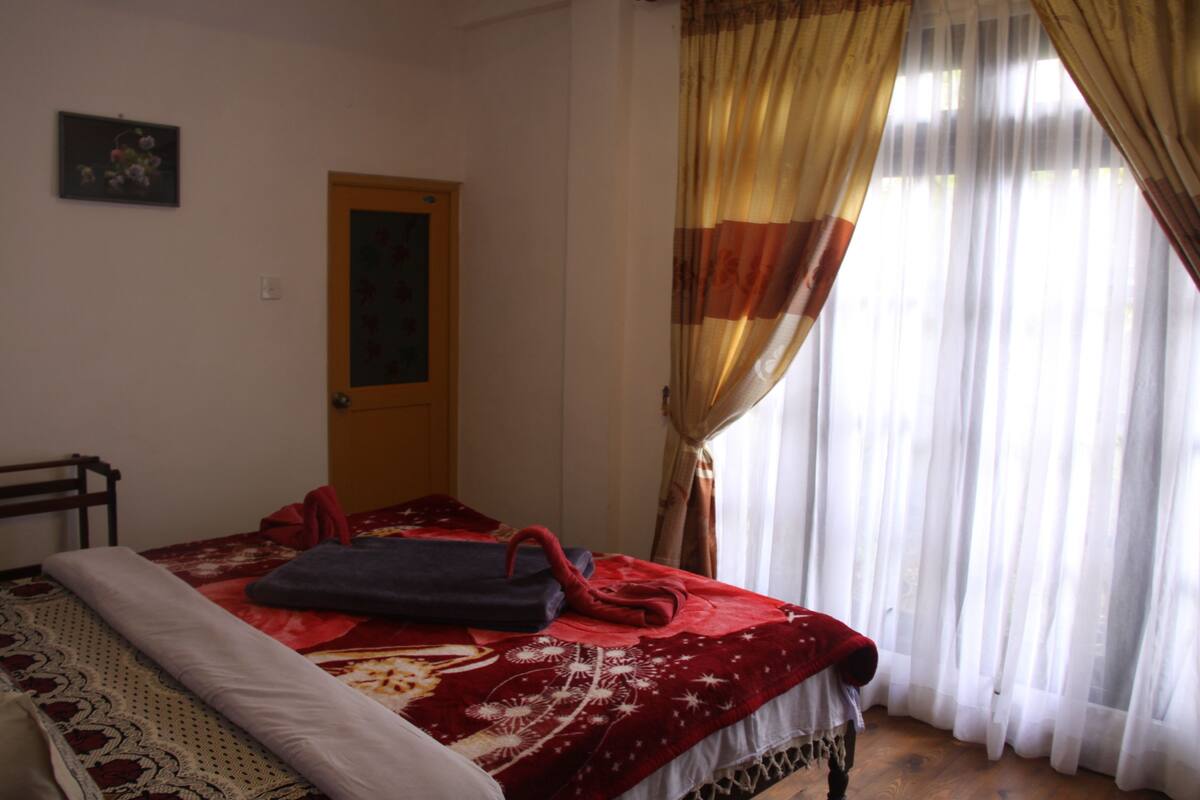 A bedroom with a bed, a door, and a window with curtains.