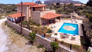Eine Steinvilla mit Swimmingpool, Sitzgelegenheiten im Freien und Blick auf die umliegende Landschaft.