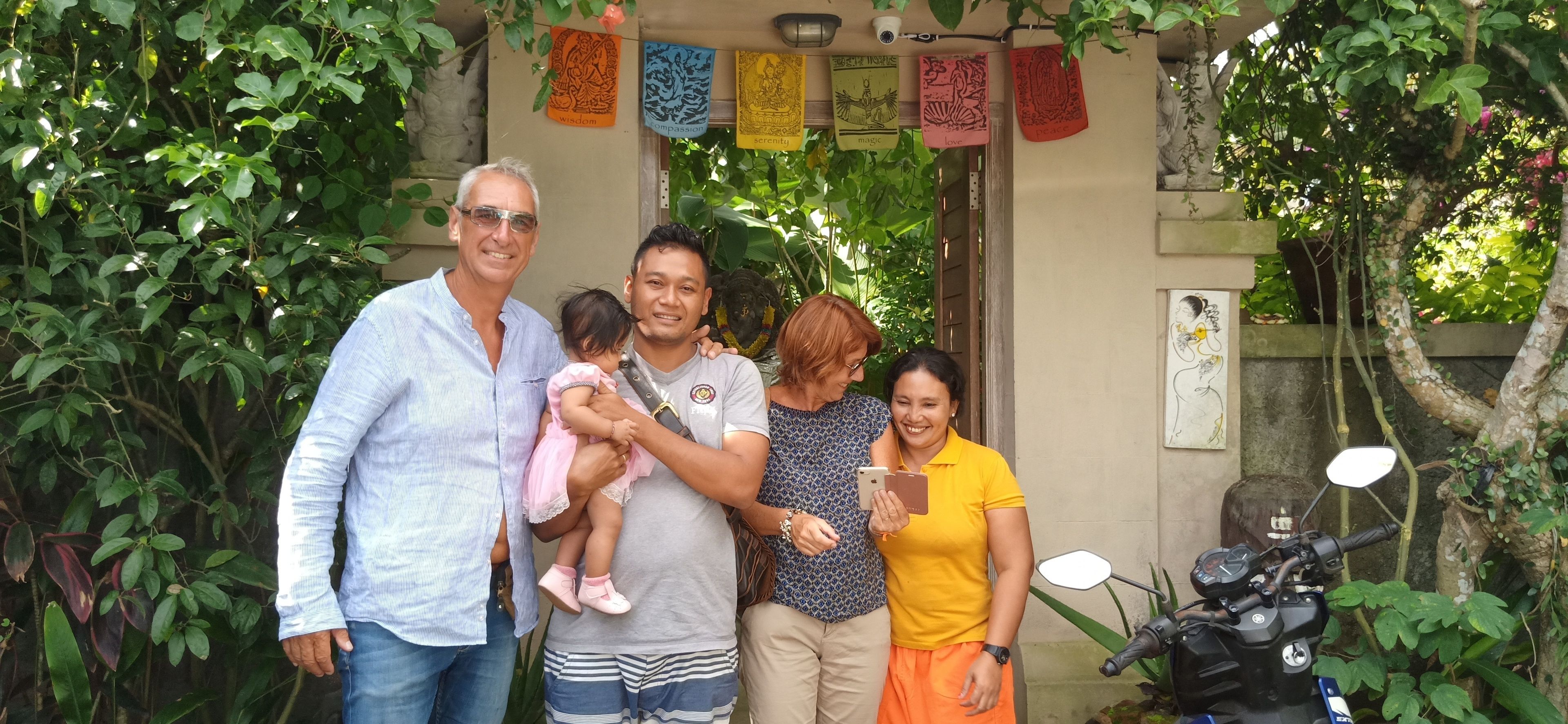 A family standing in a garden with a motorcycle parked nearby.