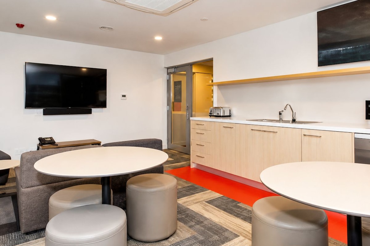 A modern kitchen with a flat-screen TV, a toaster, and a sink.