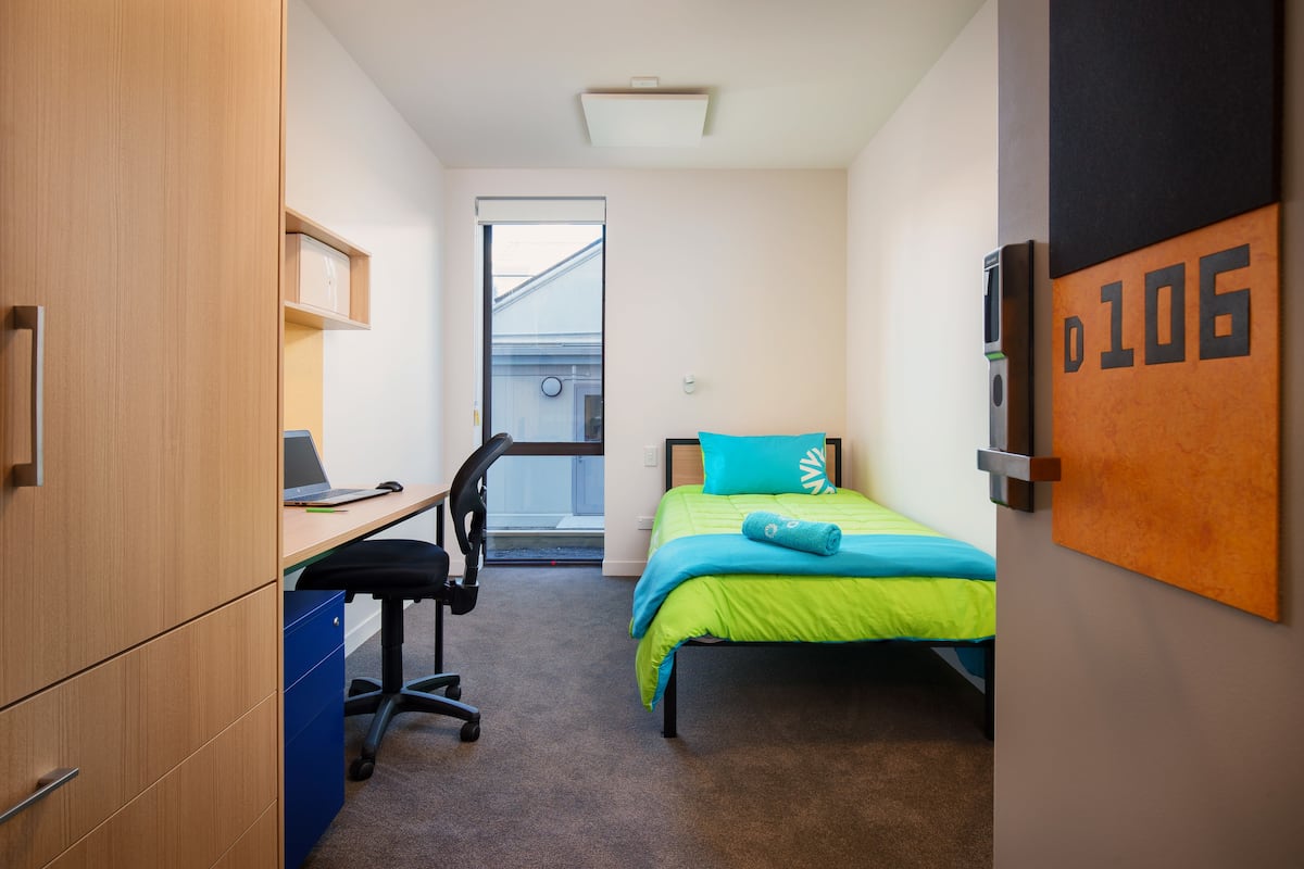 Ein gemütliches Schlafzimmer mit Bett, Schreibtisch, Stuhl und Kleiderschrank.
