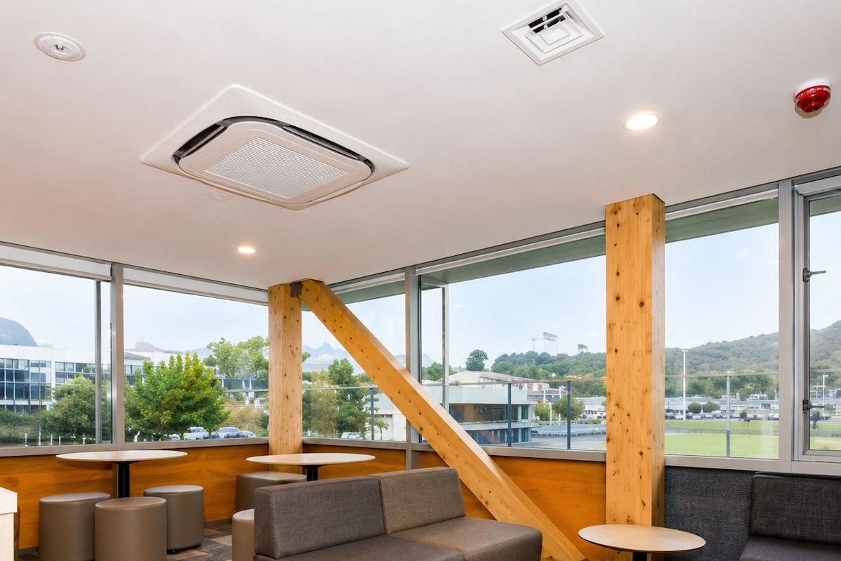 A modern interior with a sofa, round tables, and a wooden staircase.