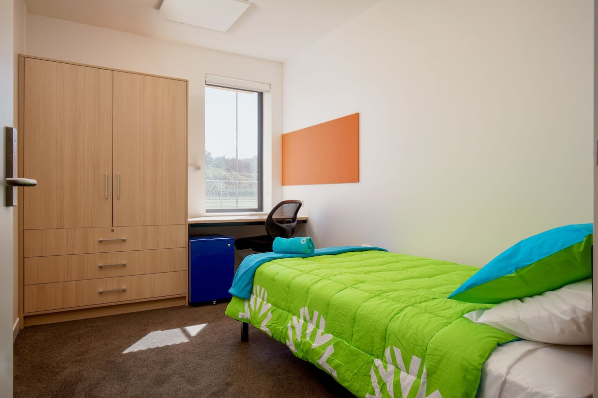 Ein Schlafzimmer mit Bett, Schreibtisch und Kleiderschrank.