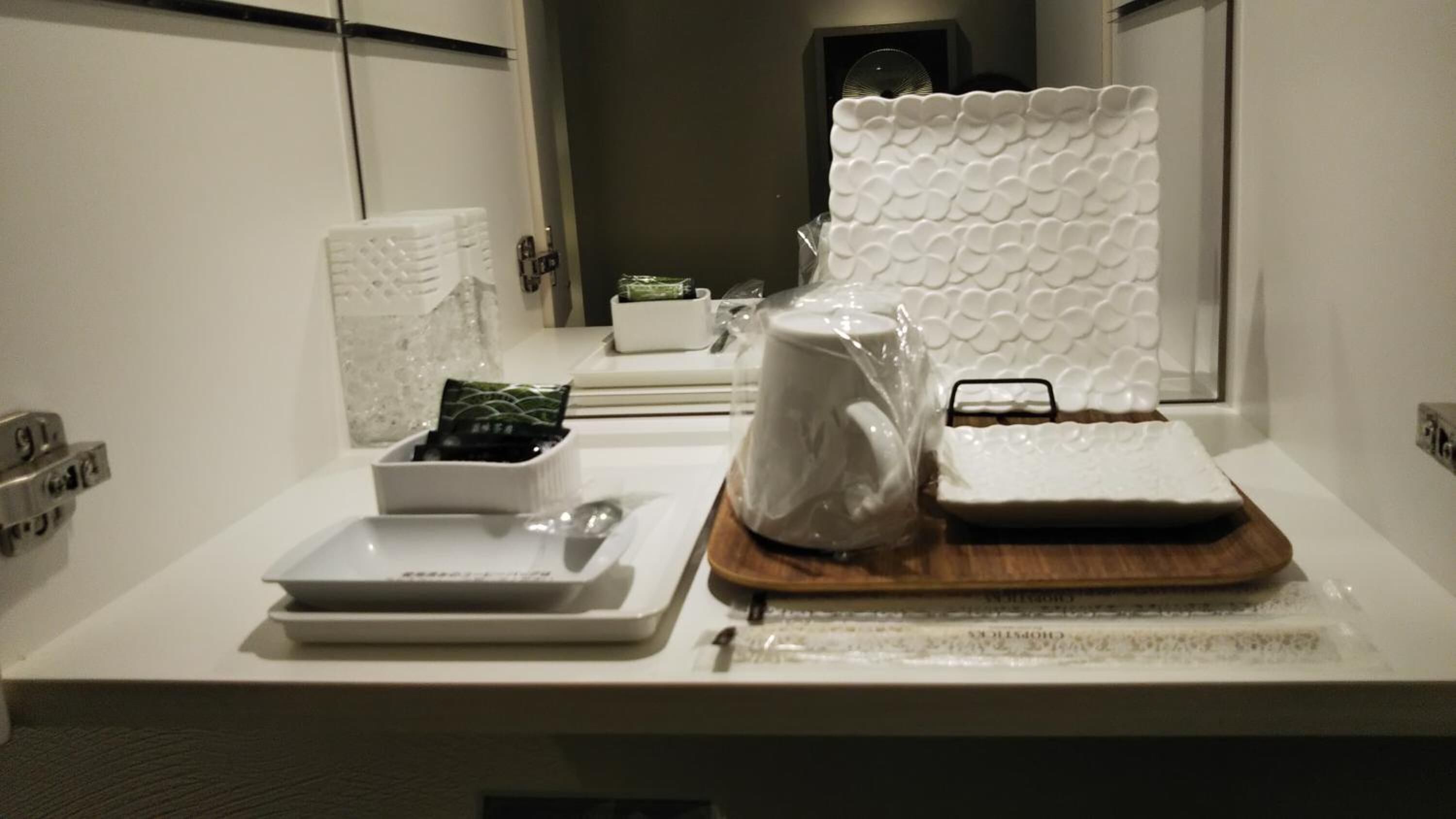 Une salle de bain propre et moderne, avec un comptoir blanc, un lavabo, un miroir et un espace douche.