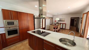 Una cocina moderna con armarios de madera, electrodomésticos de acero inoxidable y una isla central con fregadero.
