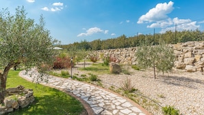 A stone pathway leading through a landscaped garden with olive trees and a stone wall. - Casale La Desdemona beautiful farmhouse surrounded by greenery with private pool (Sutri)