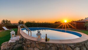 A swimming pool with a stone wall, a lounge chair, and a lantern. - Casale La Desdemona beautiful farmhouse surrounded by greenery with private pool (Sutri)