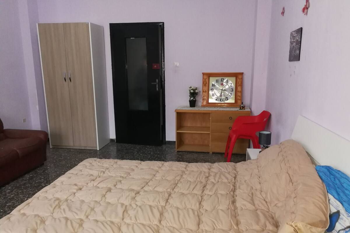 Un dormitorio con cama, armario, escritorio y silla.