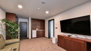 A modern living room with a flat-screen TV, a sofa, a small kitchen area, and a potted plant. - Sea & Moon Tourist Hotel (Incheon)