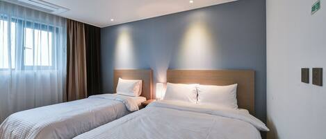 A hotel room with two beds, a nightstand, and a window with curtains.