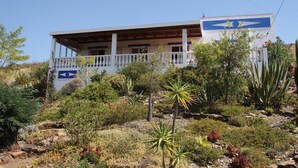 Un edificio con un balcone, circondato da diverse piante desertiche e rocce.