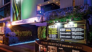 Entrada de hotel con un letrero que indica servicio gratuito y una pantalla digital con información sobre precios.