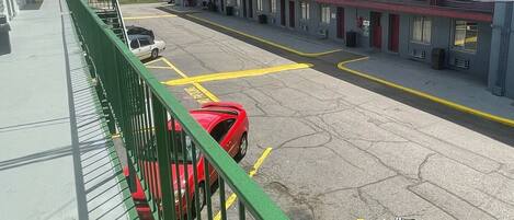 A parking lot with a red car parked near the building.