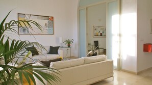 A modern living room with a white sofa, a glass coffee table, and a potted plant. - Luxury, light & spacious loft-apartment  great for longer stays, private parking (Jerez)