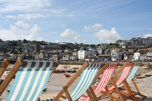 Beach chairs lined up on a sandy beach with a town in the background.