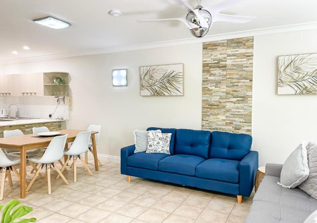 A modern living room with a blue sofa, dining table, and chairs.