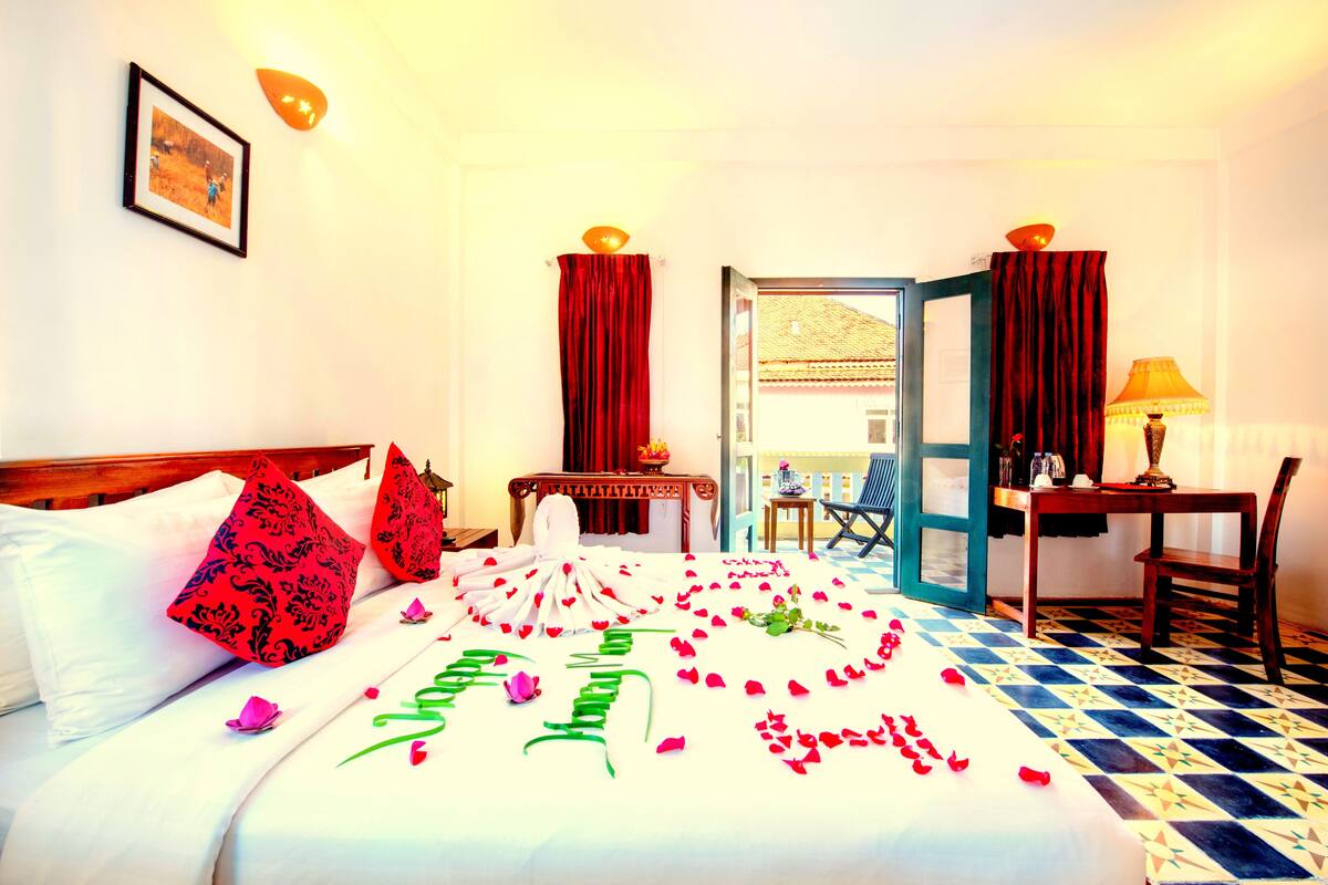 A hotel room with a bed, a desk, a chair, and a view of the outside.