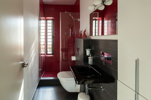 A modern bathroom with a black sink, white toilet, and red tiled walls. - Relator Terrace. 3 bedrooms, 3 bathrooms, terrace & private pool (Sevilla)