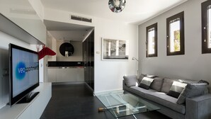 Un salon moderne avec un canapé gris, une table basse en verre et un téléviseur à écran plat.