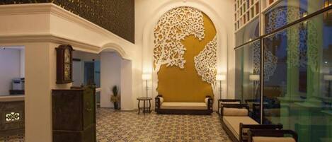 A lobby with patterned floor tiles, a large decorative wall, and seating areas.