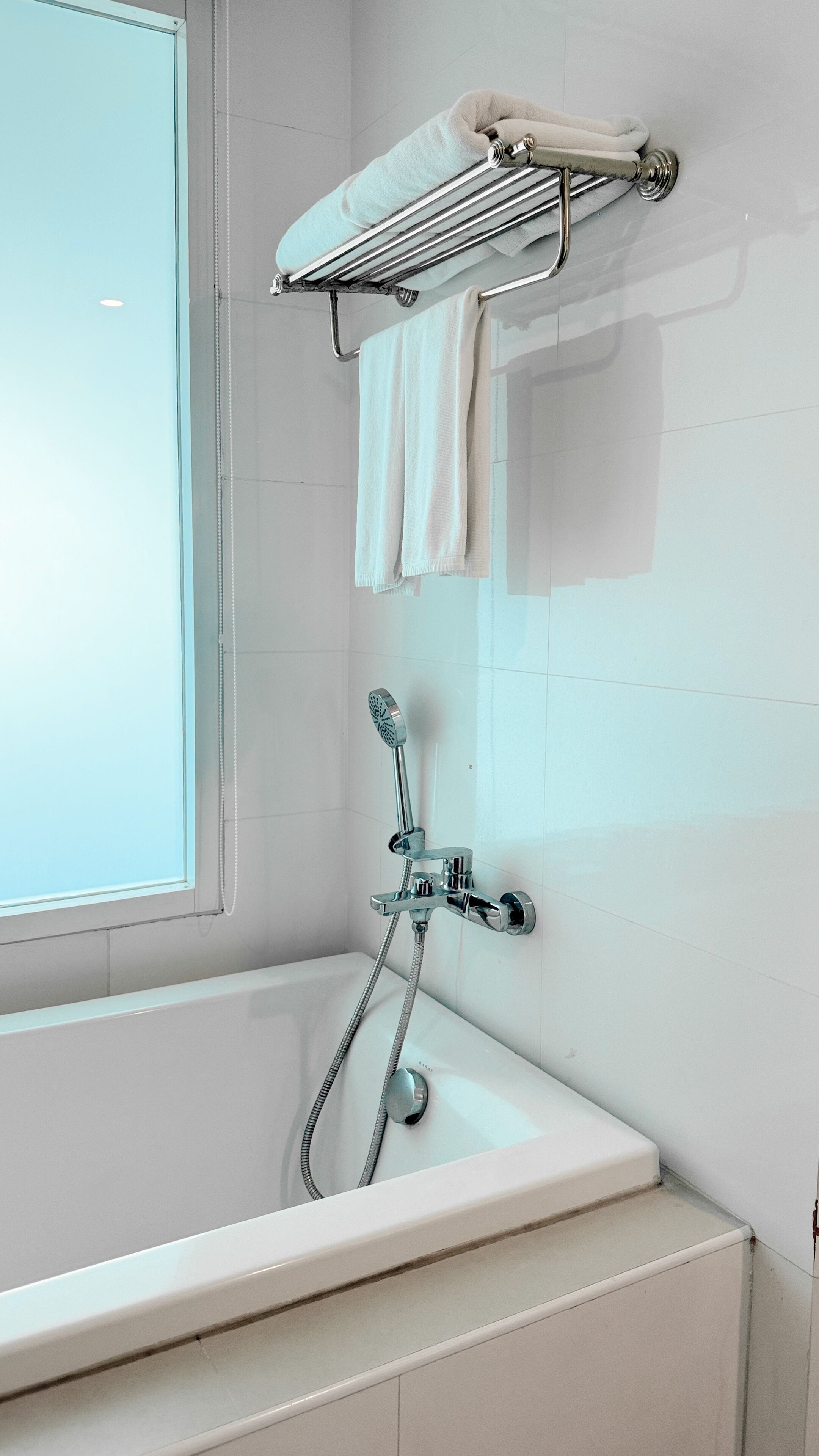 Ein Badezimmer mit einer weißen Badewanne, einer Dusche inklusive Duschbrause und einem Handtuchhalter mit zwei Handtüchern.